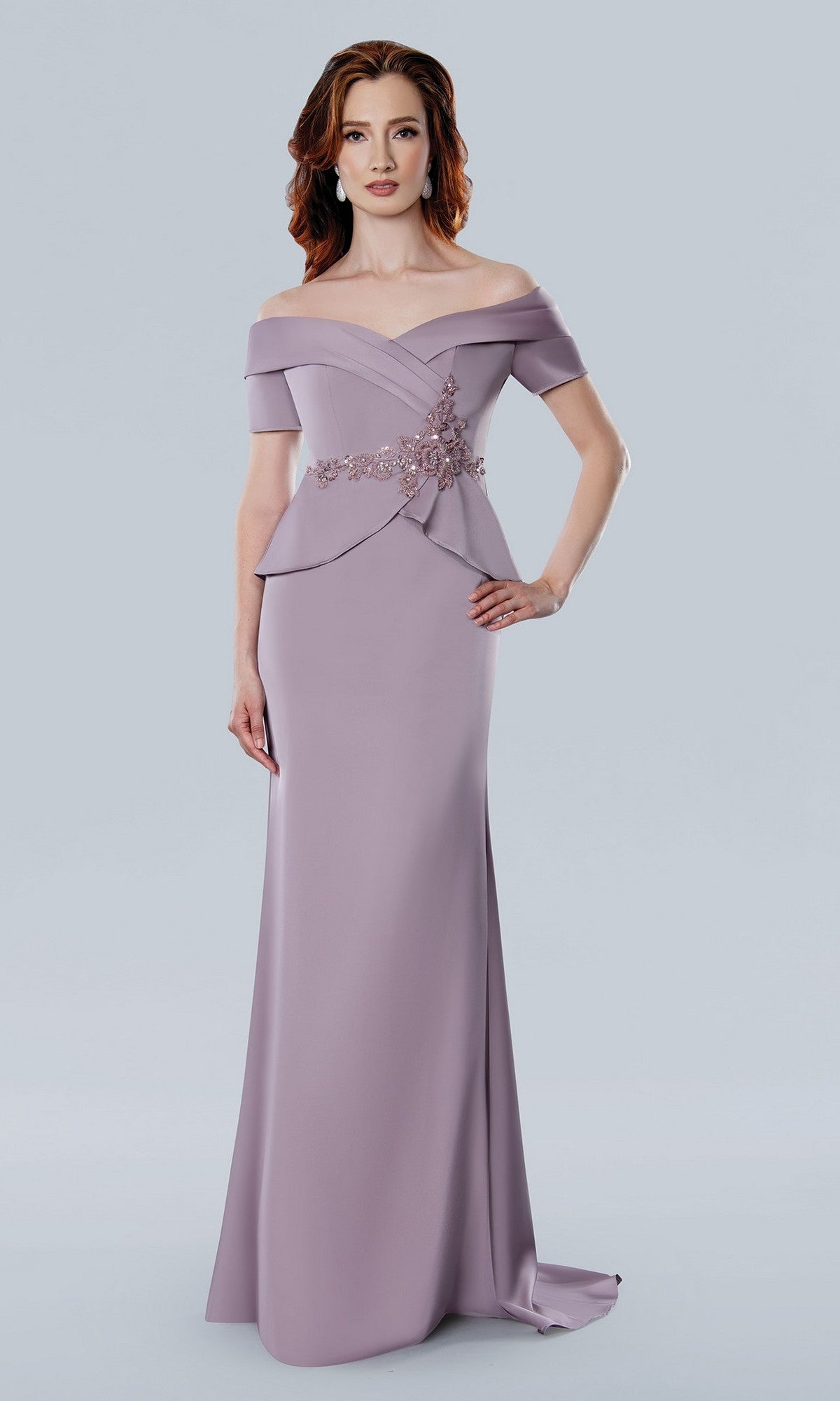 A woman in a rose Stella Couture 25309 long formal dress with off-the-shoulder sleeves, a sweetheart neckline, and beaded waistline stands against a plain light gray background.